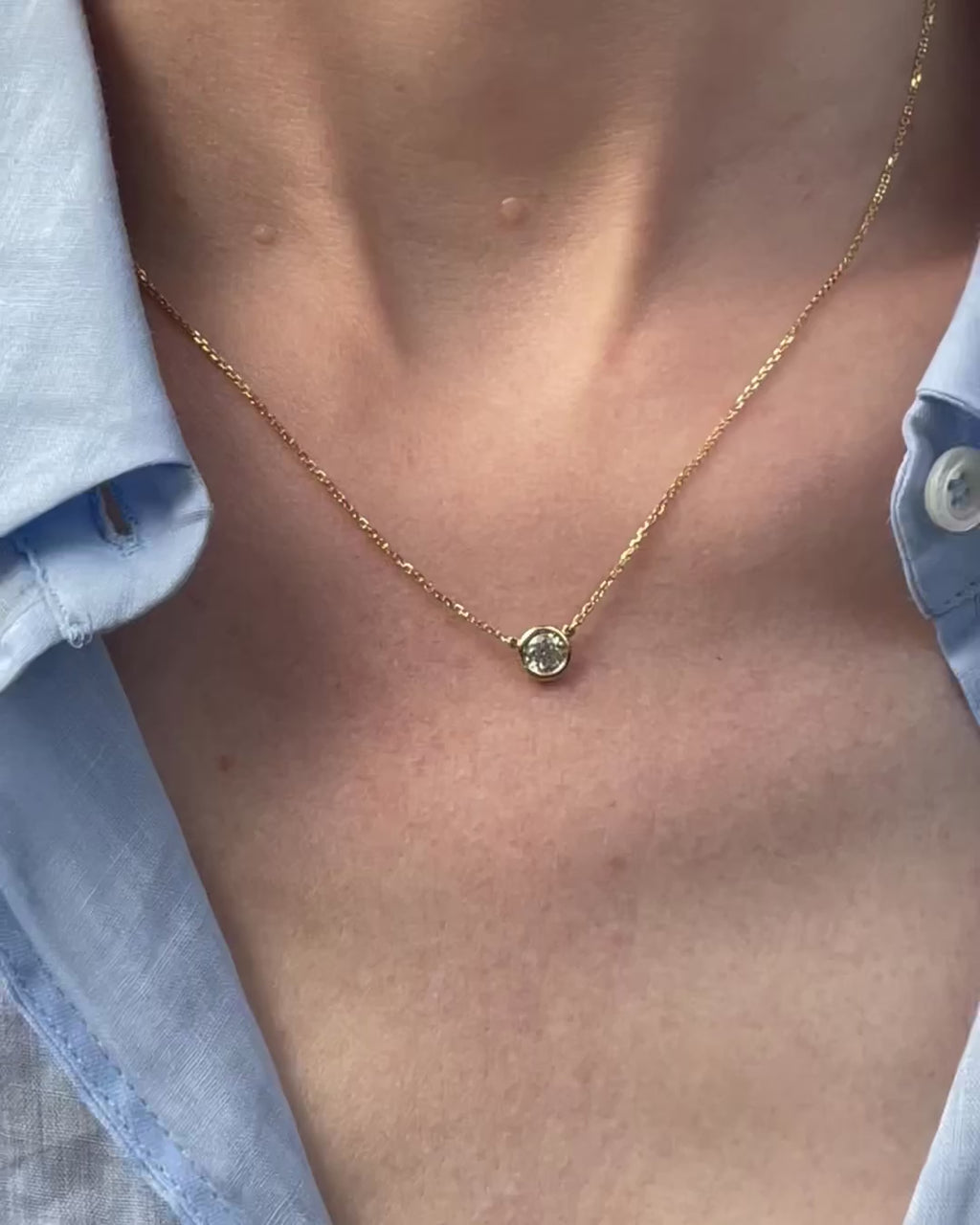 A model moving slowly, from far to close-up, showing details of the 0.40 ct bezel set diamond pendant necklace in 14k yellow gold.
