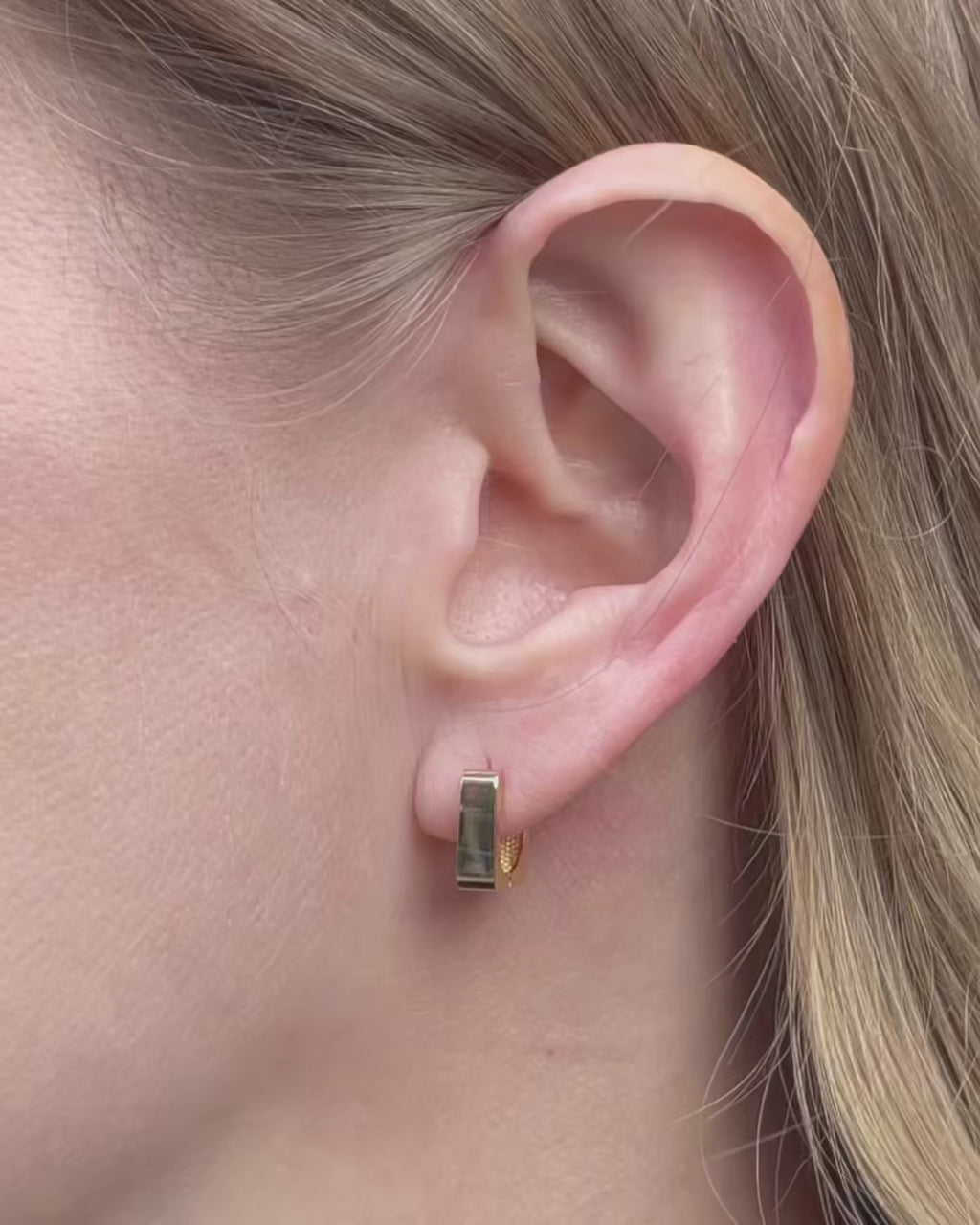 Model wearing small square huggie hoop earrings, moving slowly and showing different angles of the earrings.