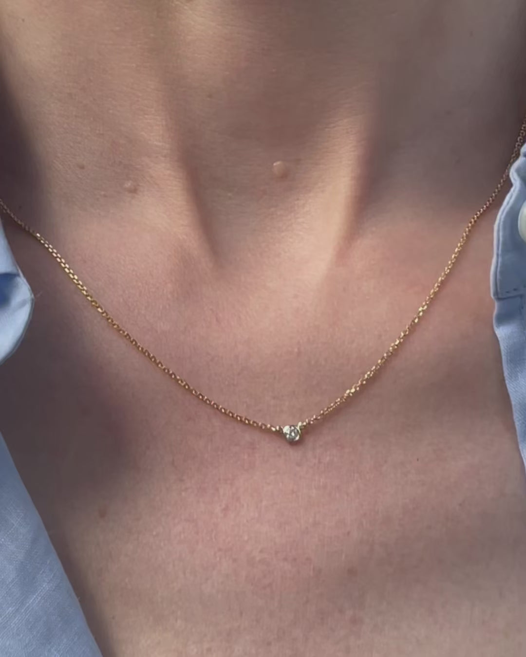A model moving slowly, from far to close-up, showing details of the 0.05 ct bezel set diamond pendant necklace in 14k yellow gold.