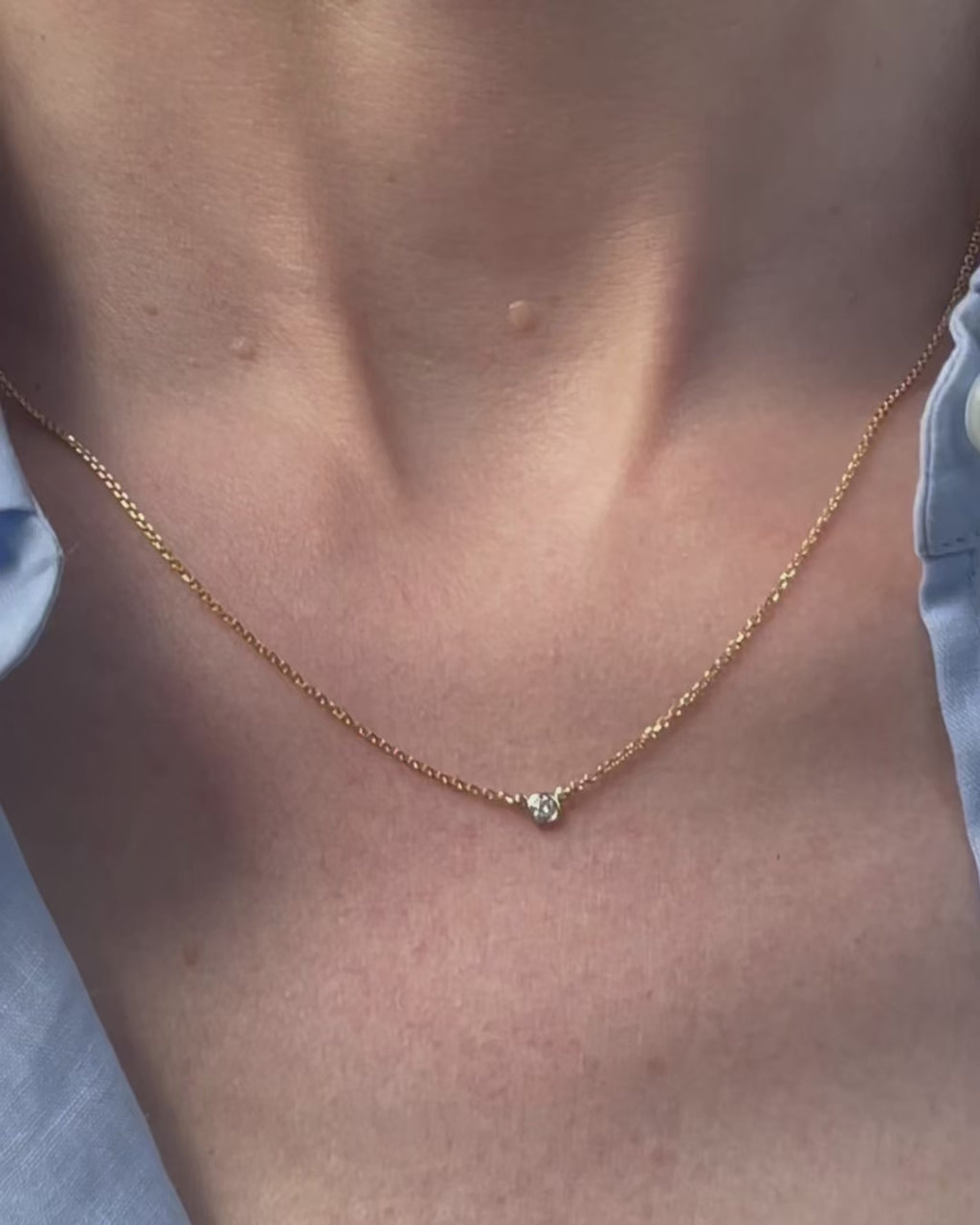 A model moving slowly, from far to close-up, showing details of the 0.05 ct bezel set diamond pendant necklace in 14k yellow gold.