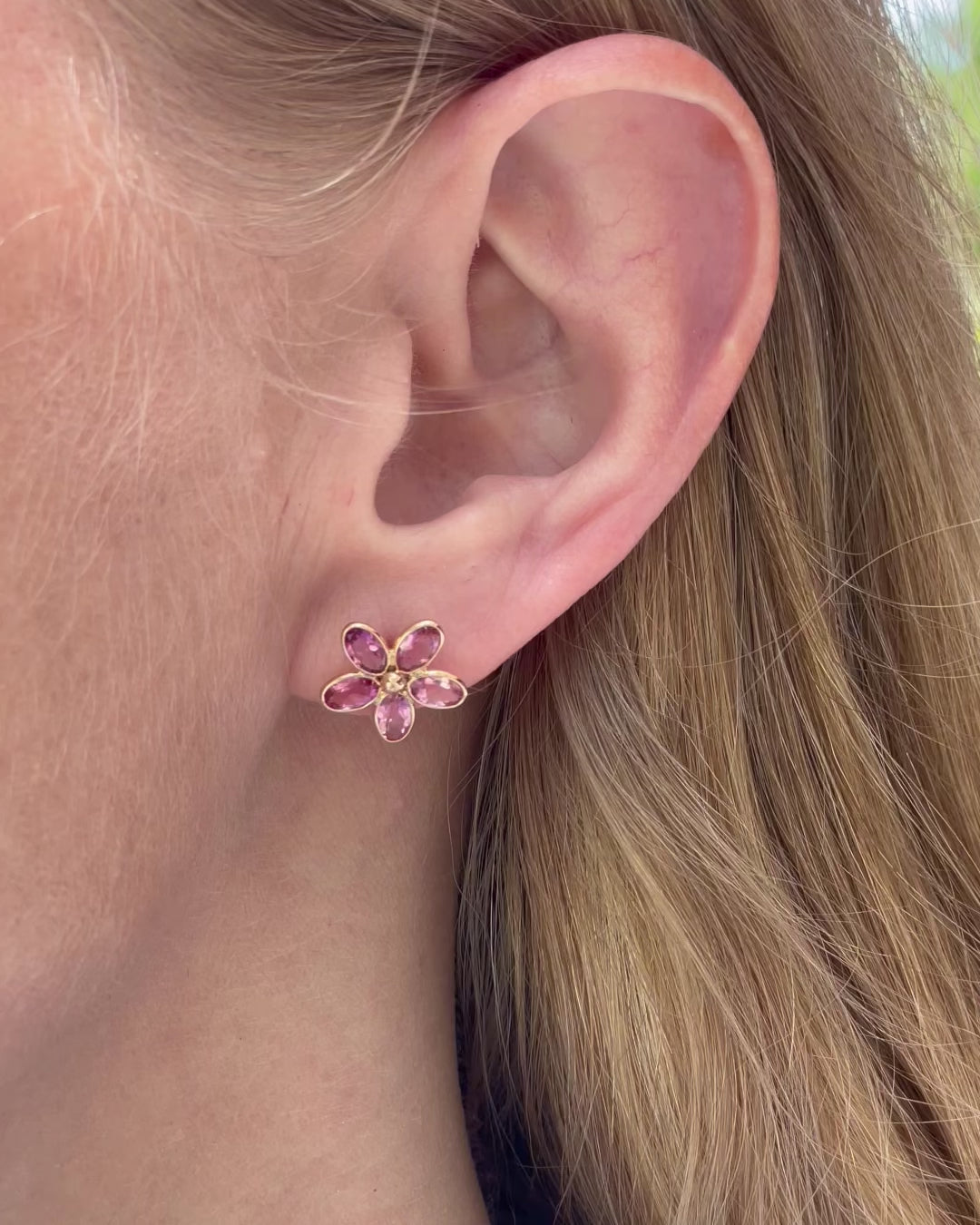 A model slowly moving, showing different angles of pink sapphire flower stud earrings.