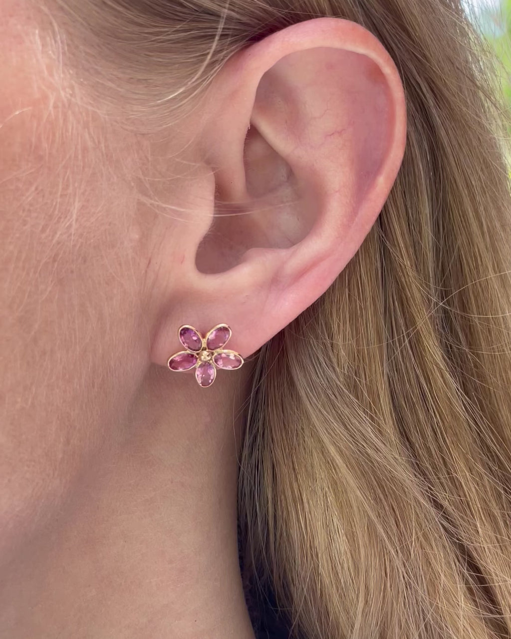 A model slowly moving, showing different angles of pink sapphire flower stud earrings.