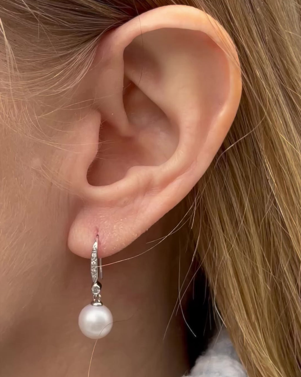 Close-up of a model wearing freshwater pearl and diamond dangle drop earrings, moving gently from side to side.
