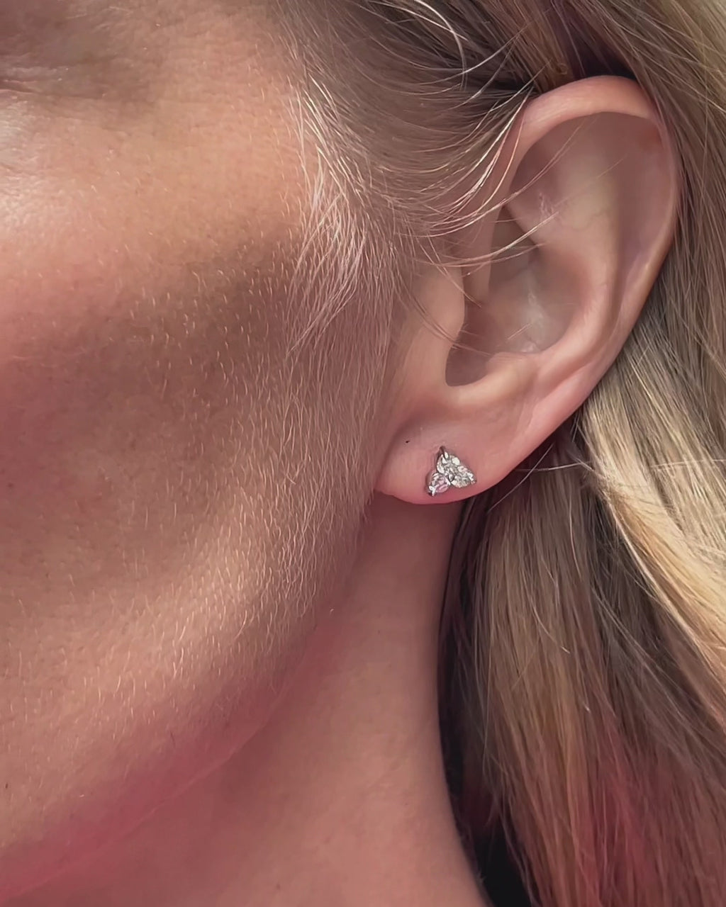 A model moving slowly, showing different angles of medium diamond trilogy stud earrings in 14K white gold.