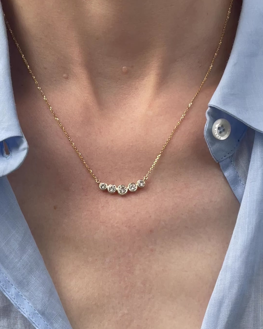 Model wearing the Bezel Set Diamond Curved Bar Necklace in 14k yellow gold (1.20 TCW), with the camera slowly zooming in to highlight the five bezel set diamonds.