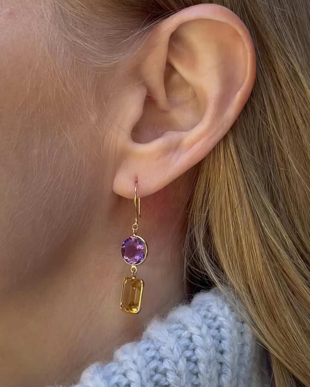 A model slowly moving, showing different angles of amethyst and citrine drop earrings.