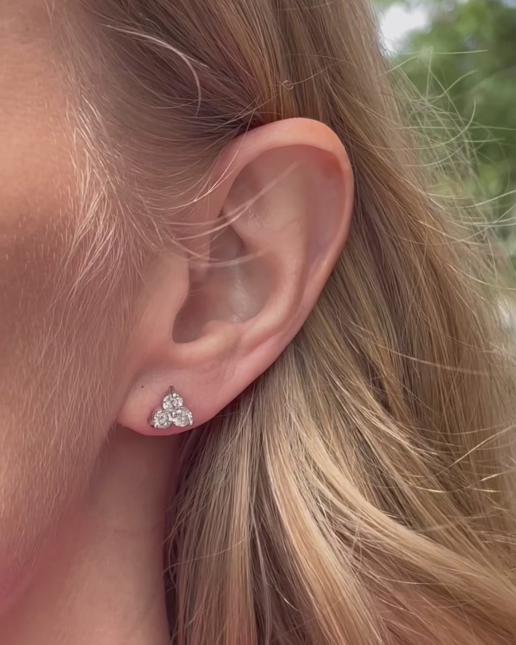 A model moving slowly, showing different angles of the large diamond trilogy stud earring in white gold.