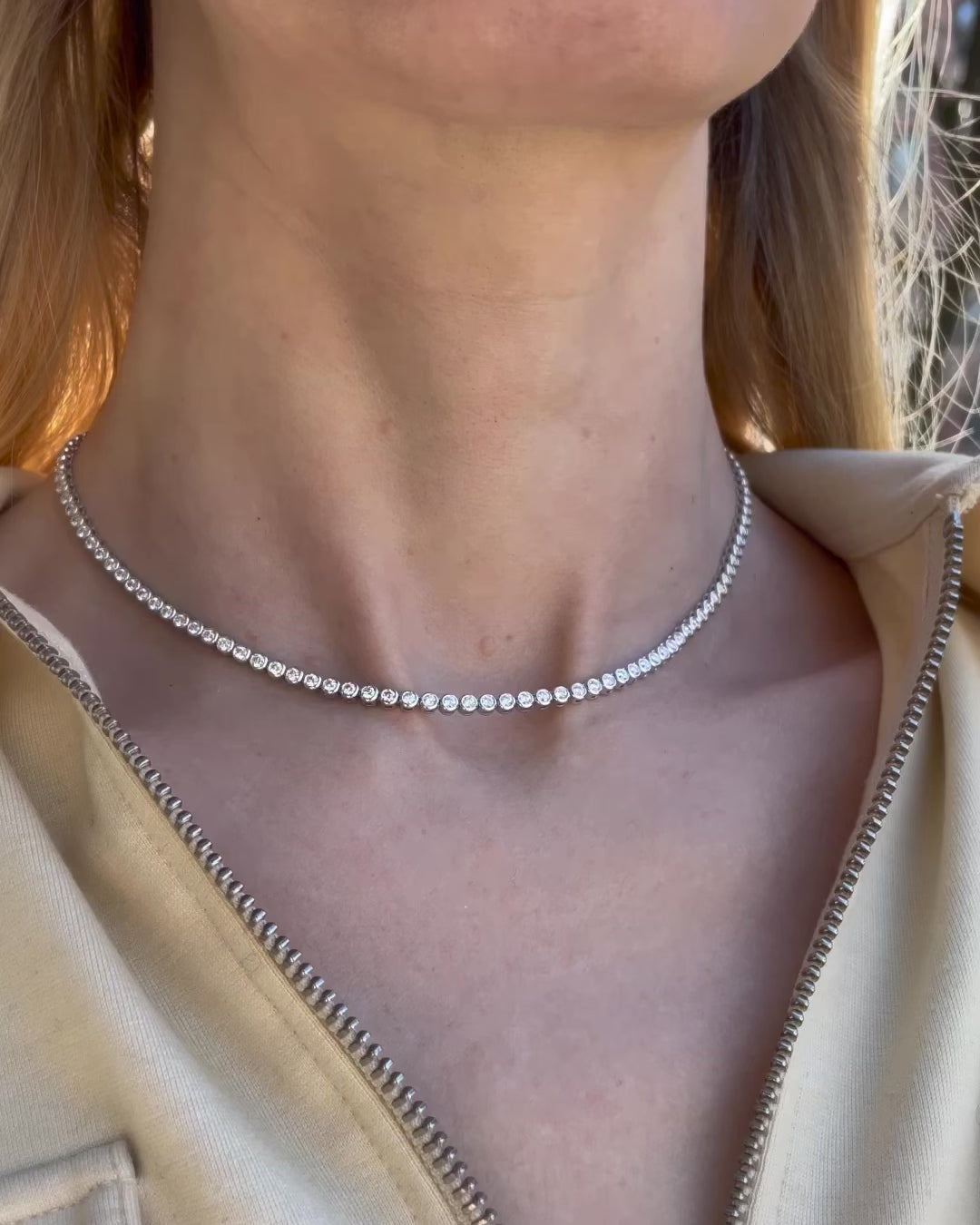 Video of a 4.71 TCW bezel set diamond tennis necklace in 18K white gold worn by a model, showcasing its continuous line of round brilliant diamonds and elegant fit along the neckline. 