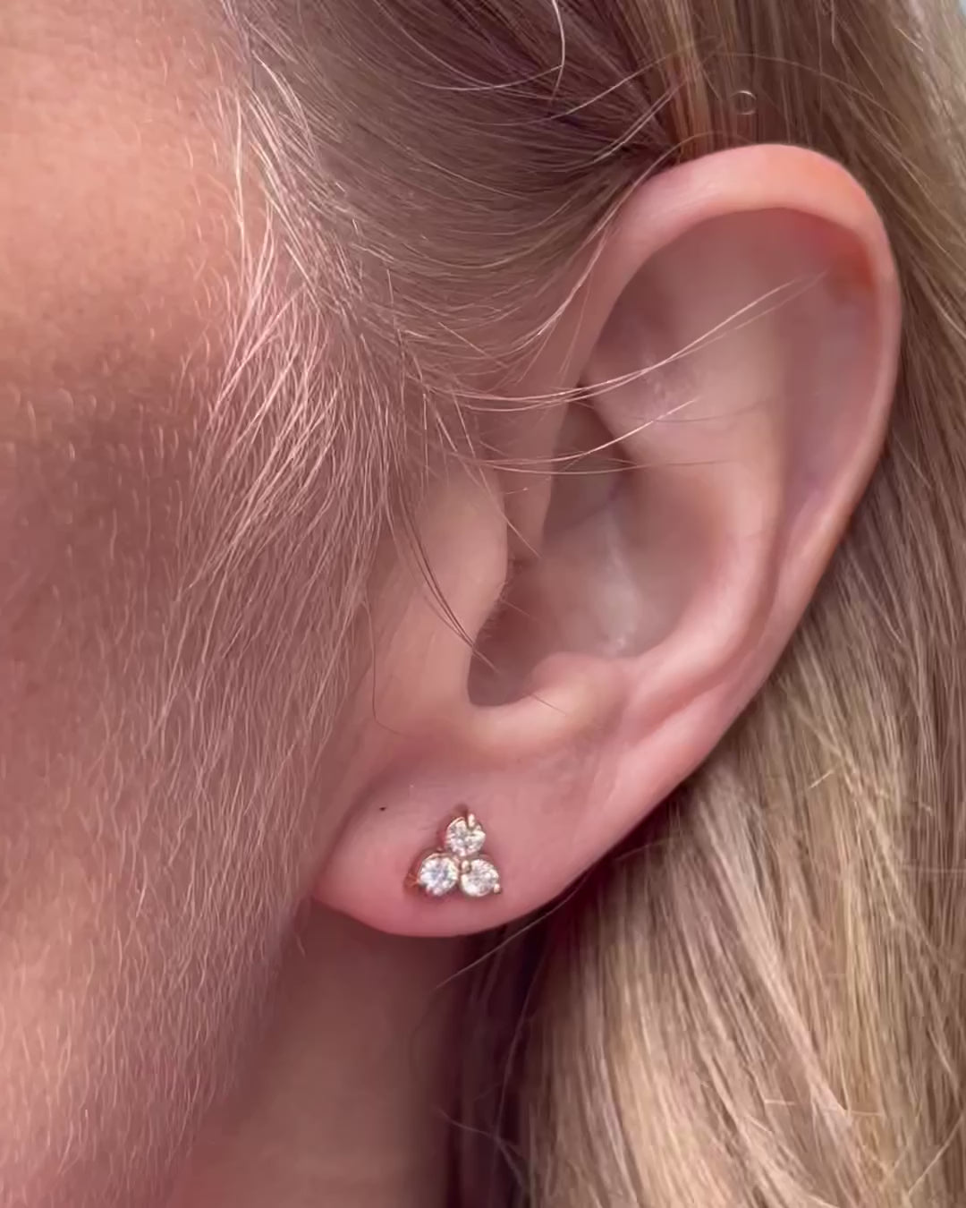 A model moving slow, capturing different angles of the small diamond trilogy stud earrings as they catch the light.