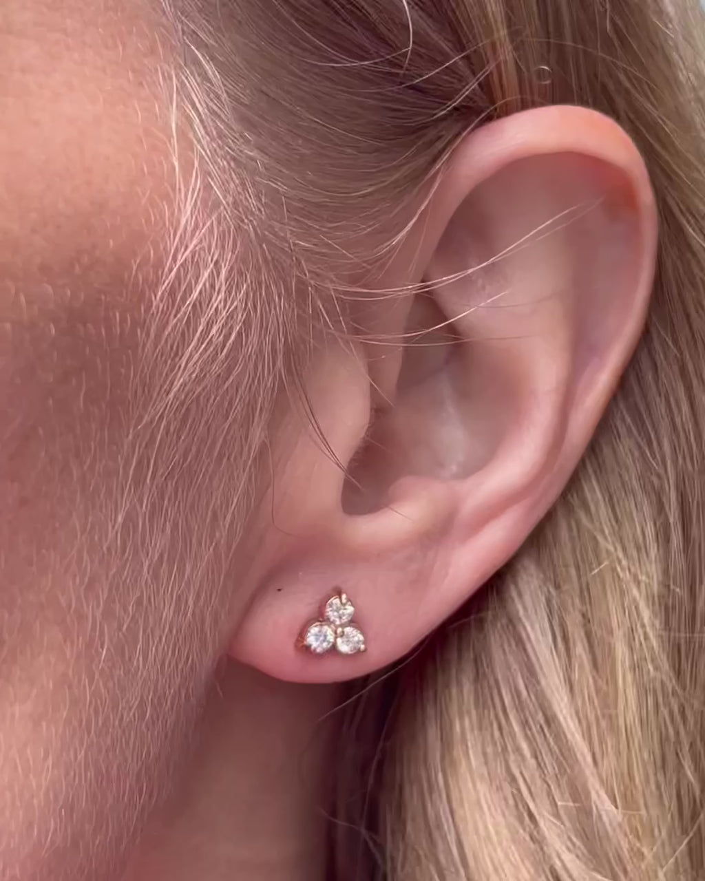 A model moving slow, capturing different angles of the small diamond trilogy stud earrings as they catch the light.