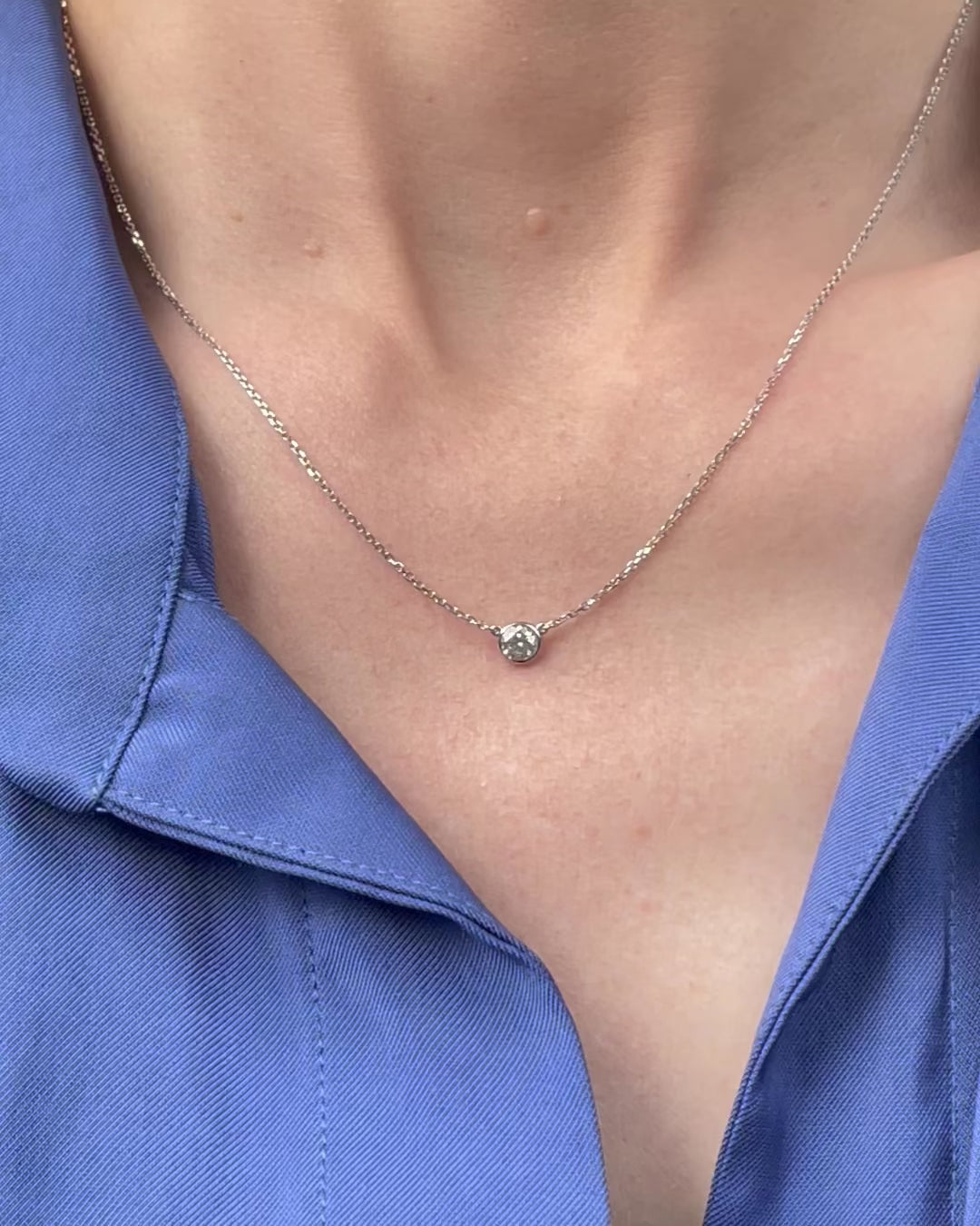 A model moving slowly, from far to close-up, showing details of the 0.25 ct bezel set diamond pendant necklace in 14k white gold.