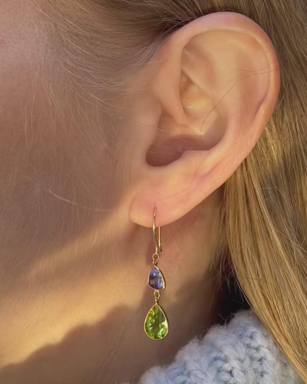 A model moving slowly, showing angles of Tanzanite and Peridot Drop Earrings in 18K yellow gold. 
