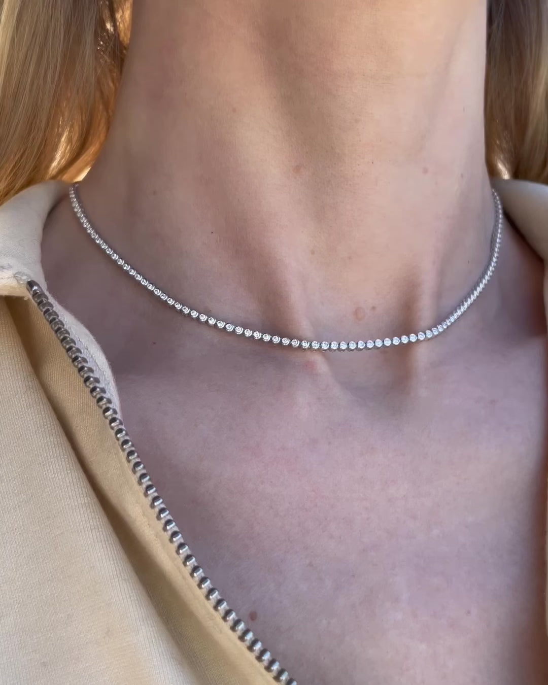 A model slowly turning to show different angles of the bezel set diamond tennis necklace - 1.88 TCW along the neckline.