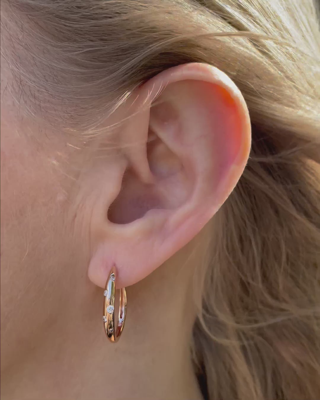 Galaxy Diamond Hoop Earrings in 14K rose gold shown in close-up, highlighting the polished gold hoops and scattered burnished-set round brilliant-cut diamonds totaling 0.18 TCW.