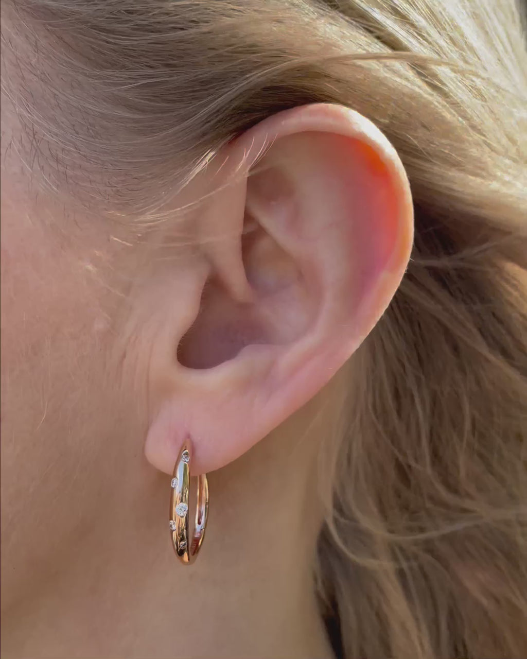 Galaxy Diamond Hoop Earrings in 14K rose gold shown in close-up, highlighting the polished gold hoops and scattered burnished-set round brilliant-cut diamonds totaling 0.18 TCW.