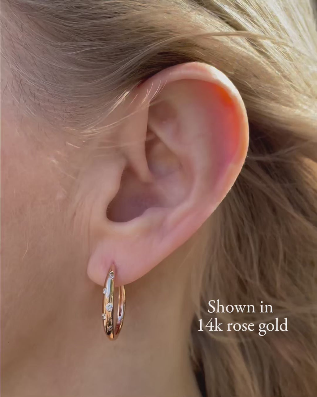 Galaxy Diamond Hoop Earrings in 14K rose gold shown in close-up, highlighting the polished gold hoops and scattered burnished-set round brilliant-cut diamonds totaling 0.18 TCW.