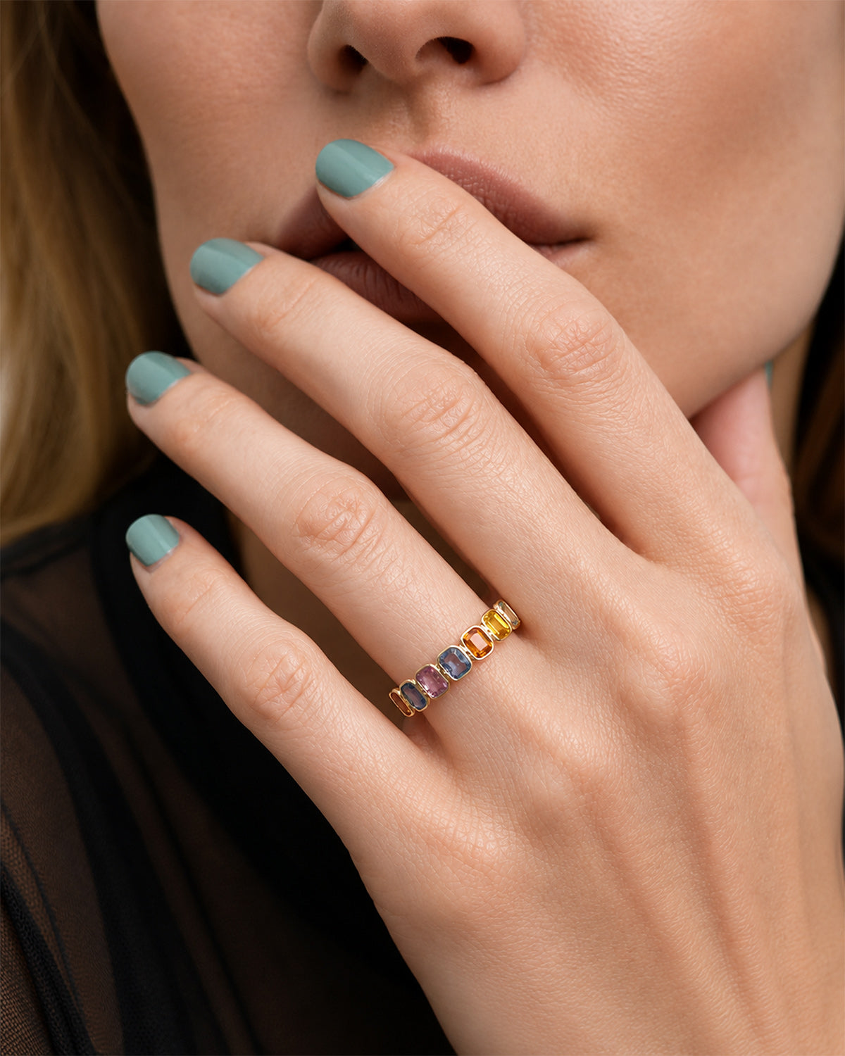 Model wearing a Rainbow Bezel Set Sapphire Ring featuring emerald-cut natural multicolor sapphires set in 14k yellow gold.