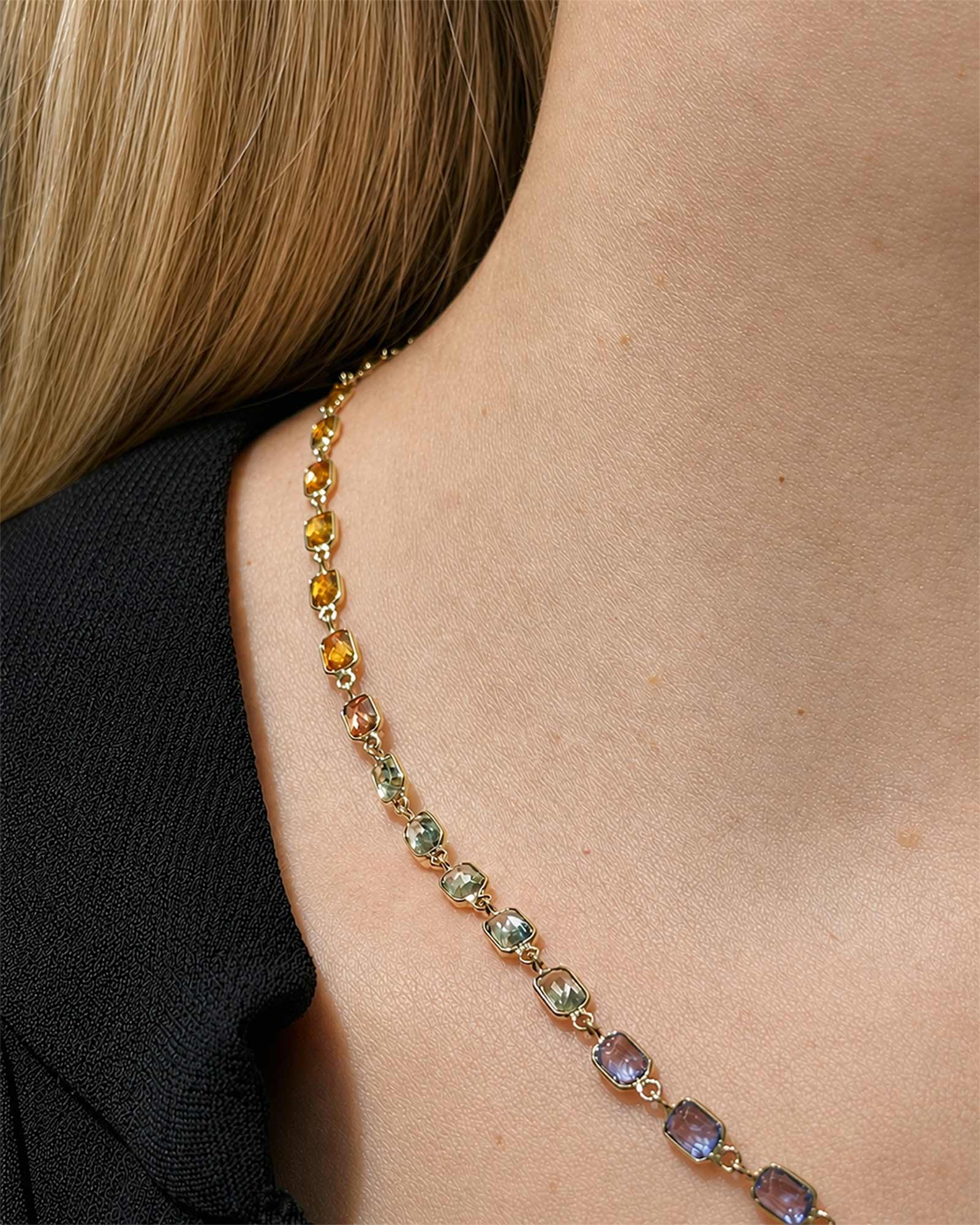 Close up details of a rainbow sapphire bezel set necklace with natural multicolor sapphires set in yellow gold.