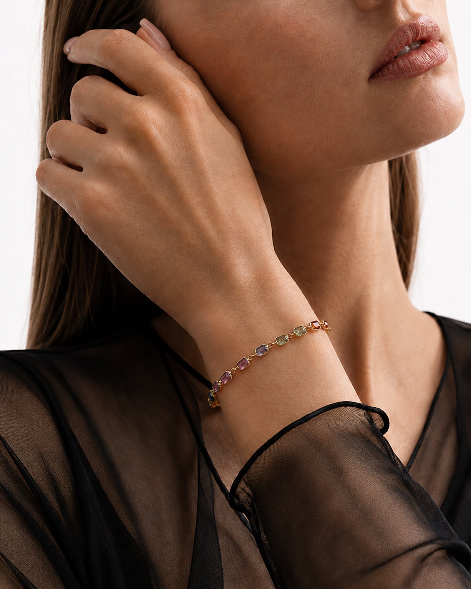 Model wearing a Rainbow Sapphire Bezel Set Tennis Bracelet featuring emerald-cut natural multicolor sapphires set in 14k yellow gold.
