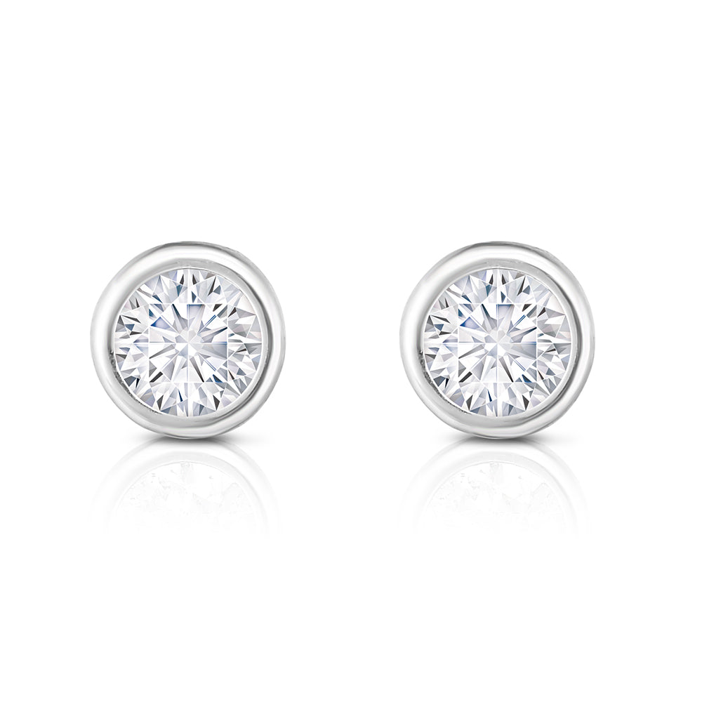 A pair of round brilliant cut diamond bezel set stud earrings in 14K white gold.