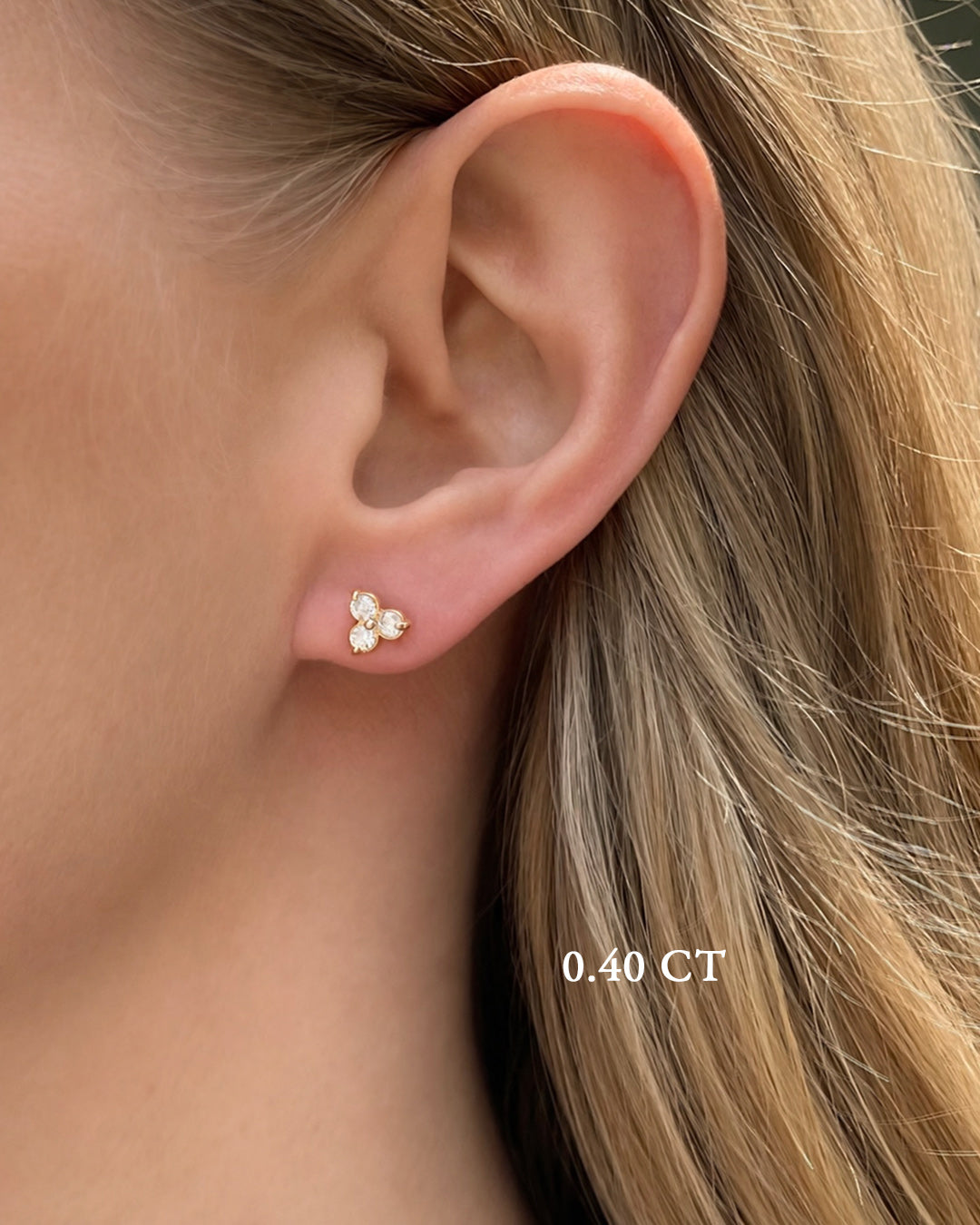 A blonde model wearing small diamond trilogy stud earrings in 14k rose gold featuring 0.40 TCW of round brilliant-cut diamonds.