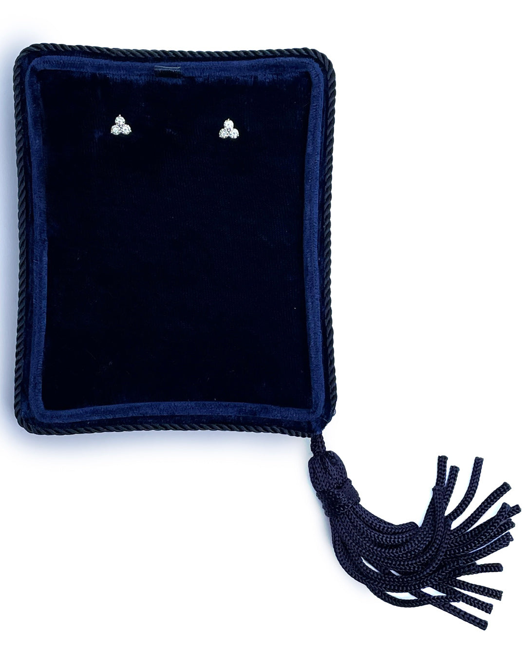 Small diamond trilogy stud earrings in 14k white gold displayed in a velvet navy jewelry box.