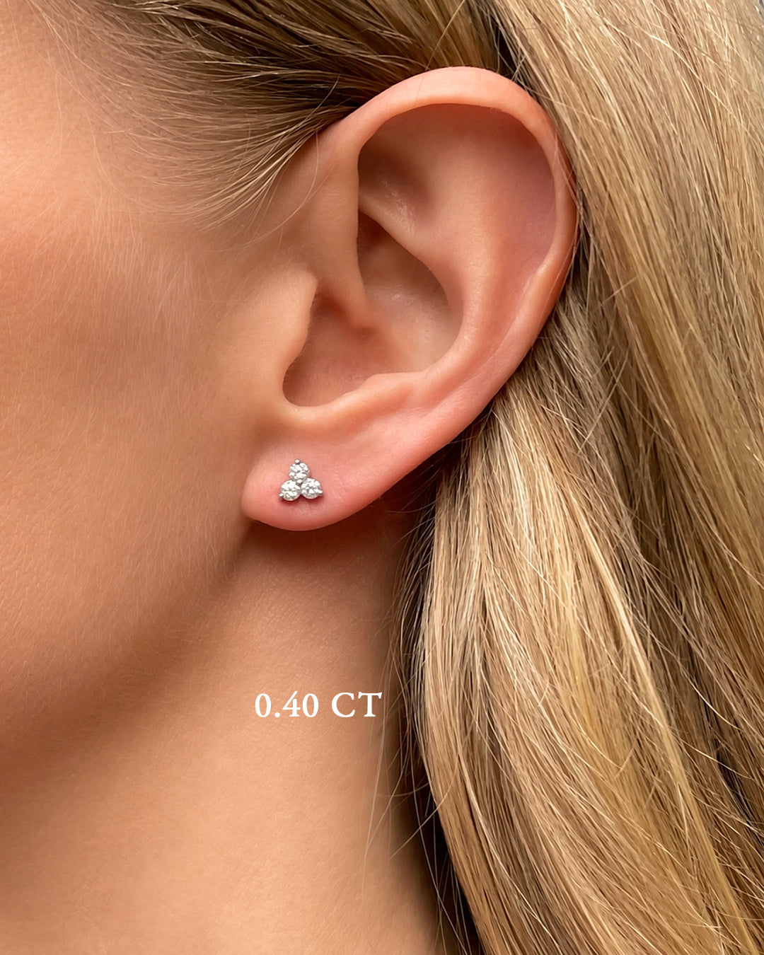 Model wearing 0.40 carat total weight diamond trilogy stud earrings featuring three round brilliant cut diamonds in a cluster design.