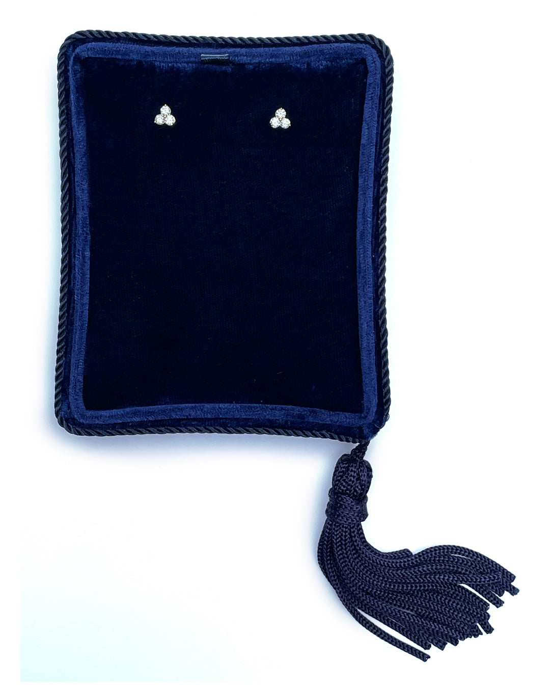 A pair of small 14k yellow gold stud earrings featuring 3 round brilliant-cut diamond clusters per earring, displayed in a dark navy velvet jewelry pouch with a braided tassel, set against a plain white background.