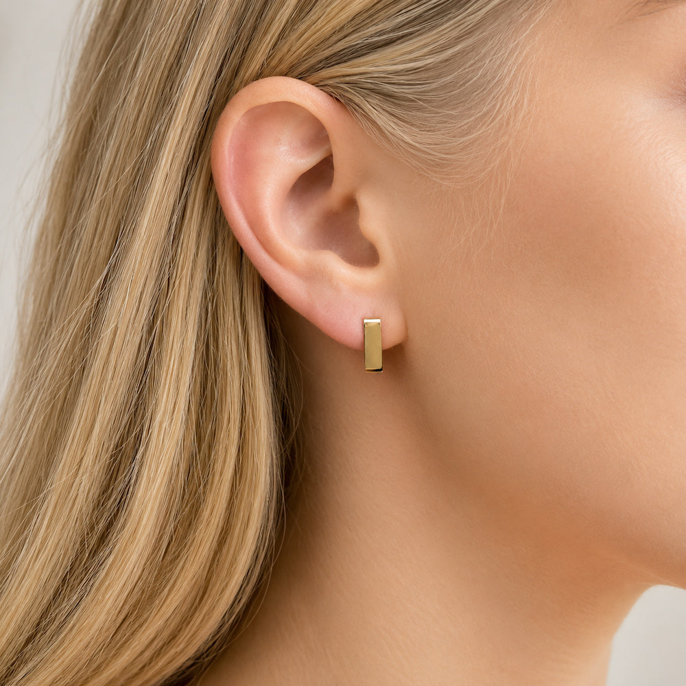 Small square huggie hoop earrings worn by a model with blonde hair.