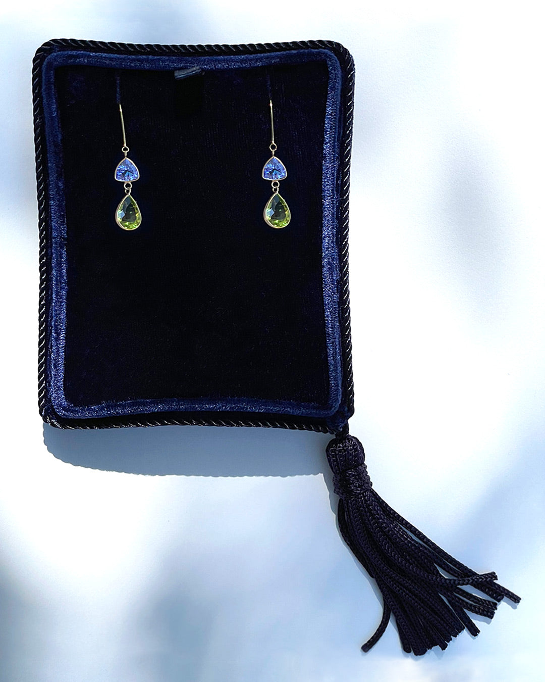 Tanzanite and Peridot drop earrings in a navy velvet Marisa Perry jewelry box.