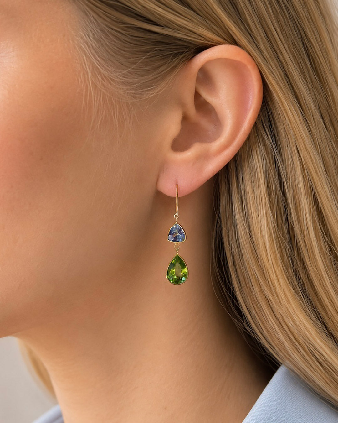 Close-up of a blonde model wearing Tanzanite and Peridot drop earrings.